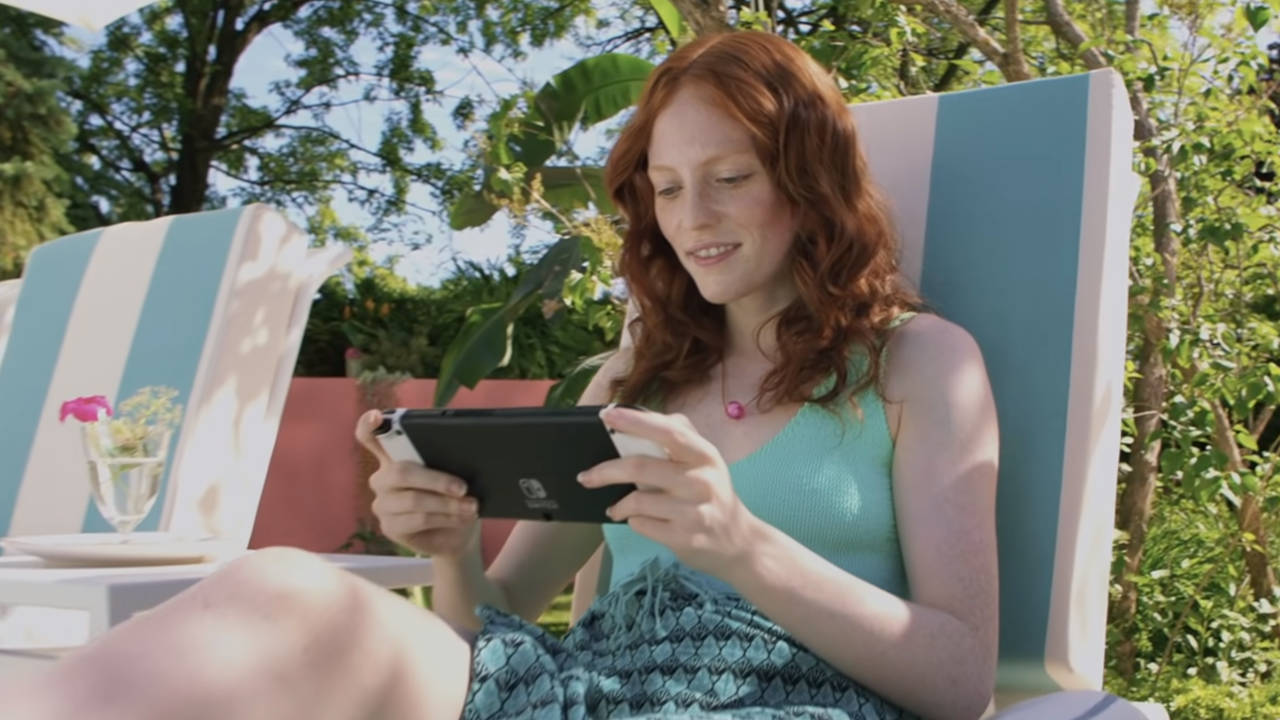 Ruda dziewczyna gra na Nintendo Switch OLED na świeżym powietrzu