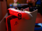Konsola PlayStation 5 z kontrolerem DualSense w odbiciu czerwonego światła.