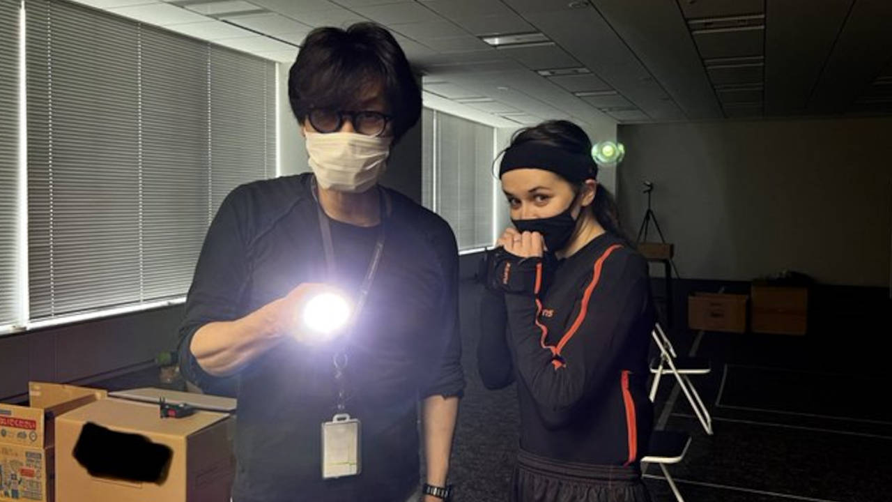 Hideo Kojima - nowa gra - zdjęcie przedstawia Hideo i aktorkę w biurze. Mężczyzna trzyma włączoną latarkę i świeci nią w stronę obiektywu
