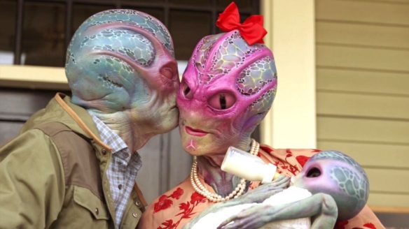 kosmita całuje żonę w policzek, a żona karmi dziecko w serialu Resident Alien