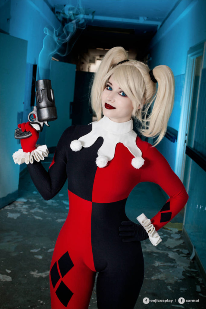 Cosplayerka przebrana za Harley Quinn stoi i trzyma pistolet w ręku