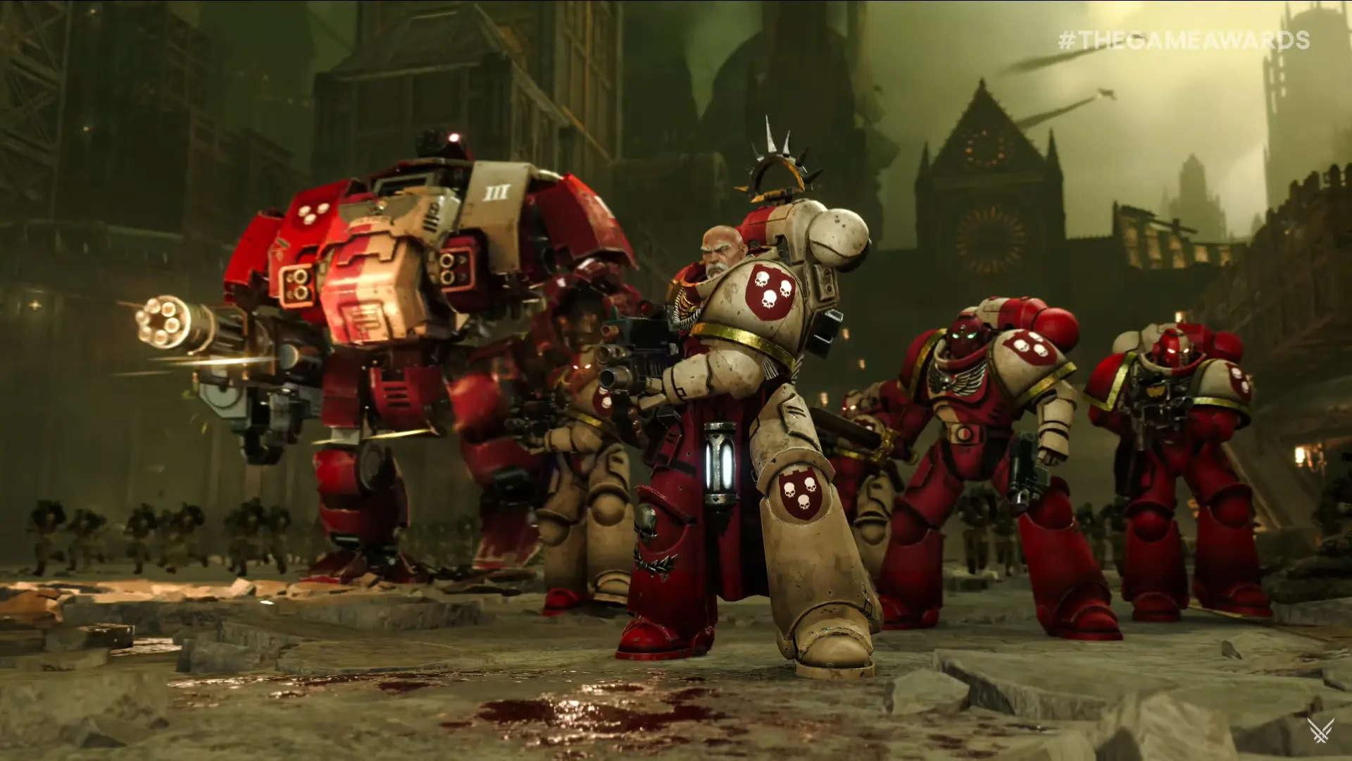 Space Marines in red armor prepare for battle, with a mech in the background.